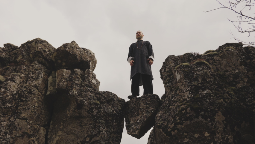 Handheld Low Angle Wide Slow Motion Shot Of Kung Fu Master Posing With Arms Out On Rocks In Iceland