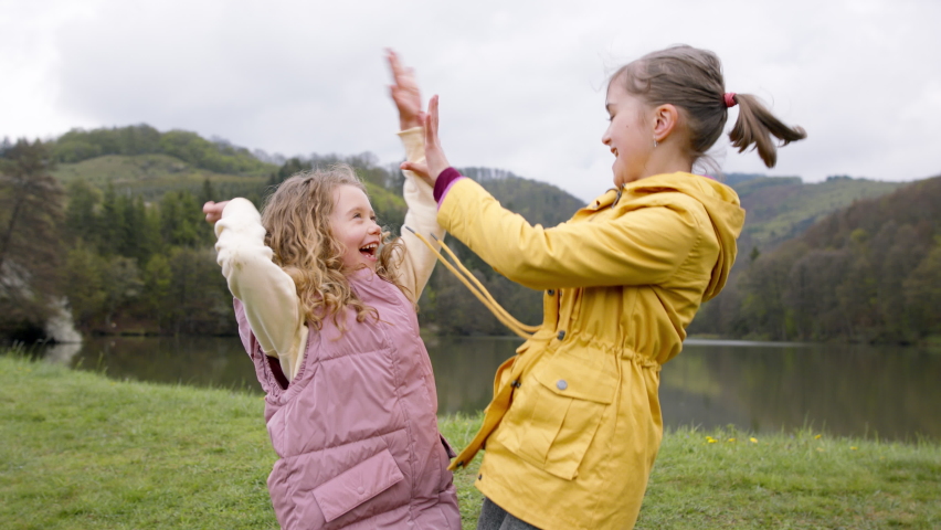 Small girls outdoors in nature, giving high five and hugging. Learning group education concept.