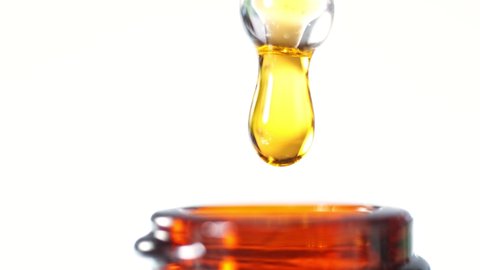 Super Slow Motion Shot of Oily Essence Drop into Phial isolated on White Background.