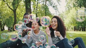 Family time, vacations, leisure together. Joyful African American famile with little kid girl blowing bubbles together, having fun on a picnic at city park, sitting on a blanket. - Powered by Shutterstock - Get 15% off with code: PIKWIZARD15