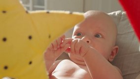 Baby face in sunlight, cute three month old baby boy rocking himself while sitting in rocking chair in front of toy mirror. High quality 4k footage