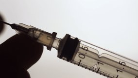 vaccination concept, drawing clear liquid into a syringe close up. bubbles inside the syringein. soft grey background. horizontal slow motion macro HD video.