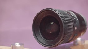Close up of digital camera lens isolated on pink background. Action. New plastic camera body, concept of photo and video recording equipment.