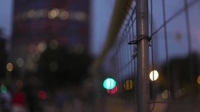 Wire mesh fence with bokeh lights and traffic defocused in the background in barcelona
