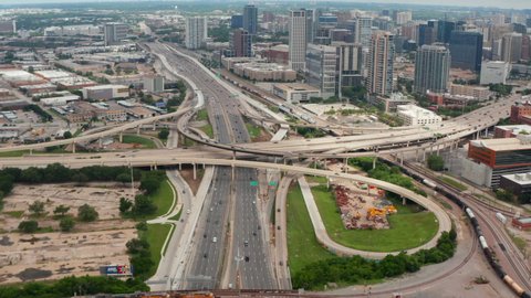Forward flying drone towards huge multilane highway intersection in town. Aerial view of traffic at rush hour. Tilt down to detail of multilevel transport construction. Dallas, Texas, US