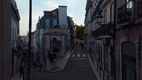 Drone camera flying through narrow street in town center. Evening elevated footage. Lisbon, capital of Portugal.