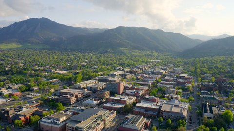 Aerial shot of beautiful flatiron mountain vista and bright green trees in downtown Boulder Colorado during an evening sunset with warm light on the rocky mountain town and summer landscape