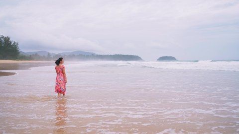 Young Asian woman walking on the beach and admiring the beauty of the sea air.