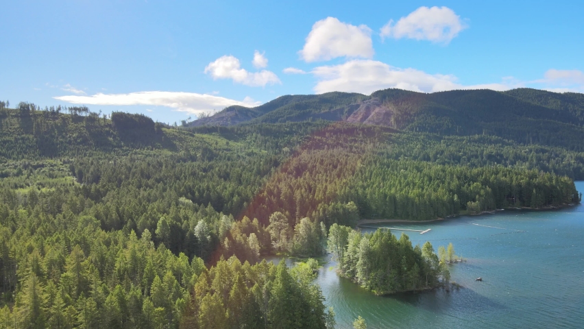 Beautiful cinematic scenery, lush green rainforest on lake and perfect clouds over foresty mountains aerial drone shot in Lake Cushman Hoodsport Mason County Washington State Pacific Northwest
