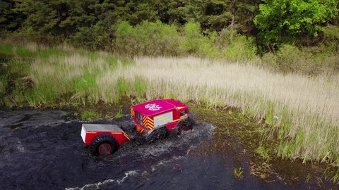 Ukrainian all-terrain amphibious rescue vehicles for rough and soggy terrain. Vehicle drives through the swamp. Aerial drone view.