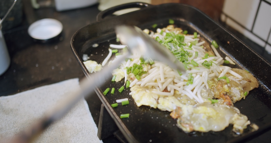 Close up cooking Thai Street Food Crispy Fried Mussel Pancake With Eggs Sprouts and Spring onions on hot iron pan at the kitchen