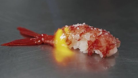 Close up of Professional chef hand use butane torch burner burning shrimp nigiri. Chef preparing healthy sushi menu on open kitchen counter bar in a Japanese restaurant