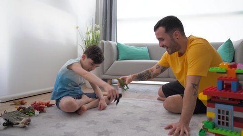 Father and son playing with toy animals, sitting on carpet at home