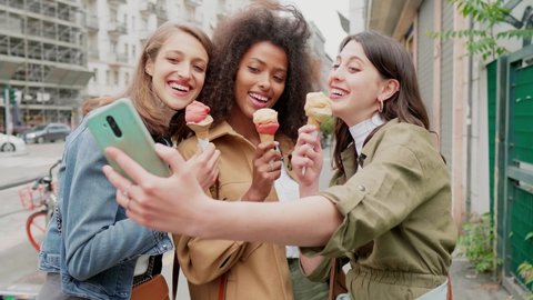 Girlfriends taking selfie in the street, eating icecream