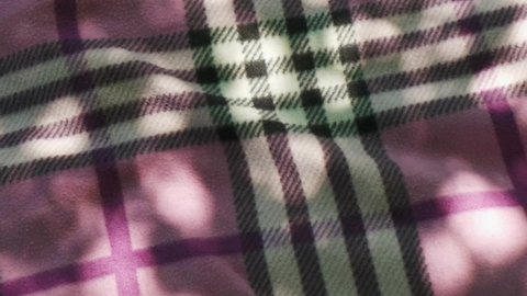 Tartan plaid cover picnic in shadow background slow motion 50p