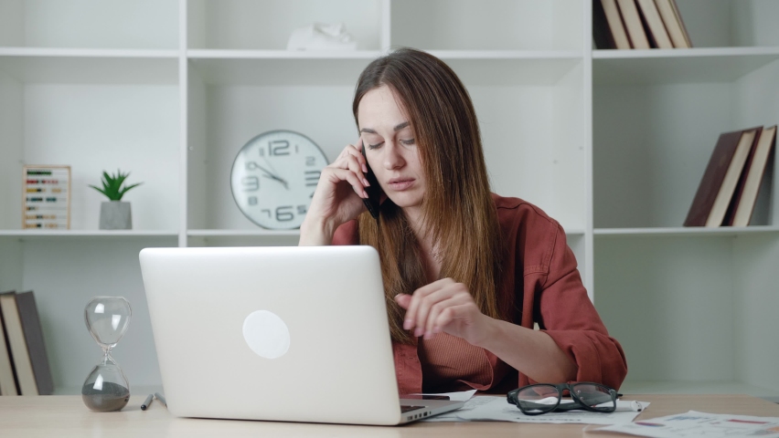Businesswoman talking on phone while using laptop