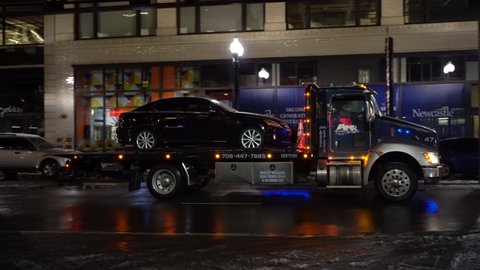 CHICAGO, USA - JANUARY 28, 2021: Truck is Towing a Car at Winter Night. Chicago Loop