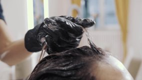 Close-up of the process of highlighting and washing a girl's long brown hair for hair health. The hairdresser in gloves prepares the strong beautiful hair of the girl for highlighting, washing and