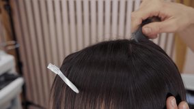 Close-up of the process of highlighting the long brown hair of a girl. The hairdresser prepares the strong beautiful hair of the girl for highlighting, combing the hair in a special beauty salon