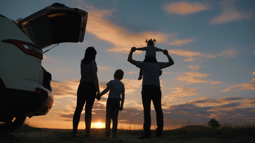 Happy friendly family. Concept of tourism, travel, summer vacation with children. Family with children traveling by car at sunset. Friendly children, parents silhouette on vacation traveling by car.
