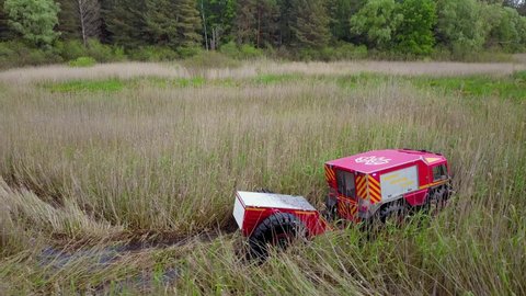 Ukrainian all-terrain amphibious rescue vehicles for rough and soggy terrain. Vehicle drives through the swamp. Aerial drone view.