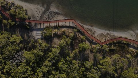A static drone video of a secret timber boardwalk winding through a coastal conservation wetland