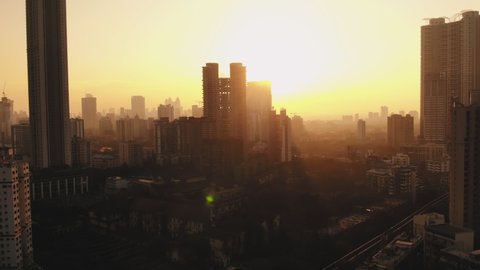 silhouette aerial View of Modern City high-rise skyscraper buildings in Mumbai City, beautiful yellow evening shot. 4k, Drone flying above the Indian city. Lockdown in India due to Coronavirus.