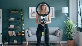 Video of sporty mature woman blogger shooting fitness workout in the living room at home.