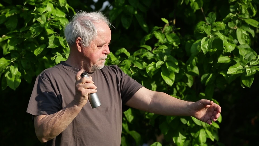 Senior man spraying repellent against kind of insects, mosquitoes and ticks, protection against kind of diseases, healthcare concept