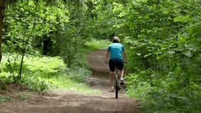 an adult woman rides a bicycle in the forest on a sunny day