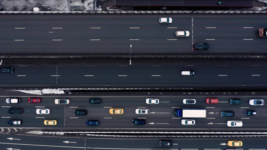 Top view drone shot of huge road with multi-lane road, many cars moving. Drone steady shot over a bridge with, transport on a highway road on winter day. Camera goes right Royalty-Free Stock Footage #1074332141