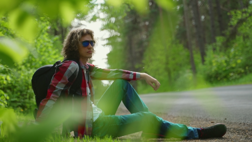 Male tourist resting by the road in woods.