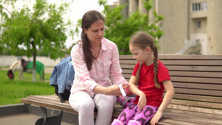 Young beautiful woman puts on little girl elbow protection for roller skating,skateboarding,cycling.