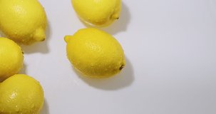 Yellow lemons lying in water, natural fruits citron on white studio backdrop, vitamins and healthy eating concept