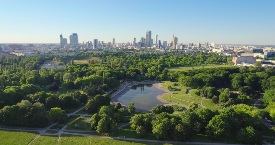 Pole Mokotowskie Warsaw Park field with lake and city skyscrapers in the background. Aerial view of the city park with lake and green trees. Summer season. Royalty-Free Stock Footage #1074339212