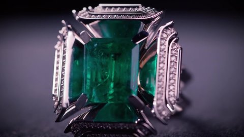 Close up of breathtaking platinum cufflinks with diamonds and emeralds. Video. Beautiful jewelry for man isolated on dark background under the spotlight.