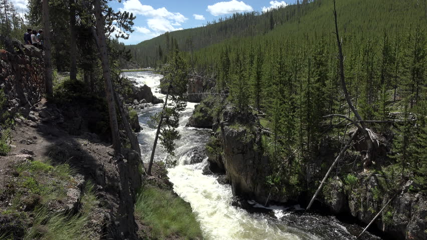 YELLOWSTONE, WYOMING - JUN 2015: Firehole Falls waterfall Yellowstone National Park 4K. 3 million visitors to Yellowstone as tourists. Geysers, hot pots and springs, river, Old Faithful attractions.