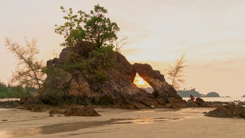 sunset in the hole of rock at Hin Thalu Phayam island
beautiful sunset in the hole of unusual rock wave eroded into the cavity like the arch with a hole 
in the middle peaceful atmosphere at Hin Thalu