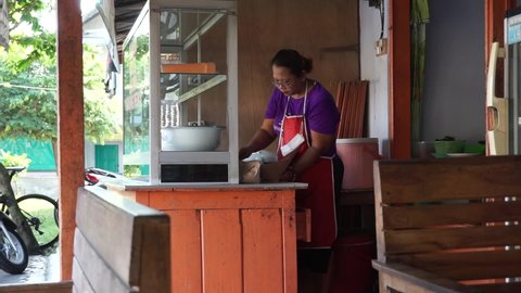 Blitar, East Java, Indonesia - May 21st, 2021 : The seller and the buyer in warung pecel do transaction. Pecel is indonesian salad with peanut sauce