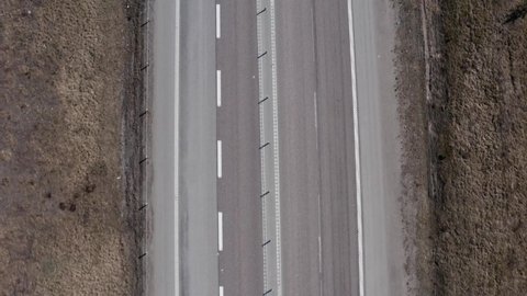 Top down shot of highway in Sweden with car and trucks with trailers driving by. Vertical shot panning upwards.
