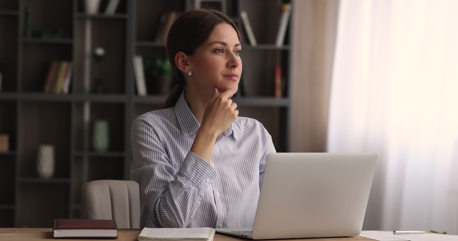 Attractive pensive thoughtful woman sit at modern homeoffice desk working remotely, writing on laptop compare information with copybook written text, do freelance online job, study, workflow concept Royalty-Free Stock Footage #1074370874