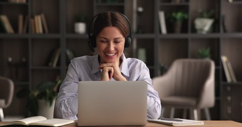 Female tutor sit at desk gives private online class remotely wear headset talking by videocall application, looks at laptop screen counsellor provide support. Negotiations use videoconference concept