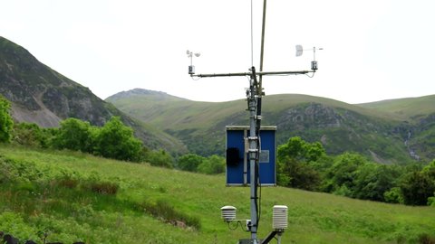 Meteorological or weather station in the mountains powered by small solar panel; an anemometer, the wind speed measuring device cups spinning slowly.