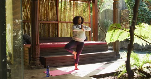 African american woman practicing yoga and meditating at vacation home. active and healthy lifestyle during vacation concept