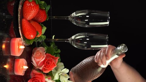 Male hand pouring champagne in glasses on Valentine's Day, 4k vertical video