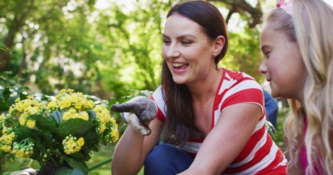 Smiling caucasian mother and daughter gardening, talking and holding yellow flowers. happy family, spending free time at home.