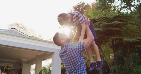 Happy caucasian son running and jumping into the arms of father in garden. happy family spending free time at home.