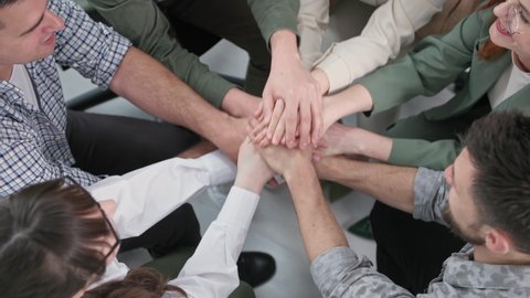 support circle, young men and women raise and lower their hands then applaud each other during work team meeting in office, top view