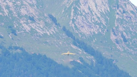 Mollis Switzerland AUGUST, 16, 2019 Small fast airplane climbs in the sky with green and gray rocks background. Hawker Hunter Mk 68 trainer military airplane of Swiss Air Force in Tiger color scheme