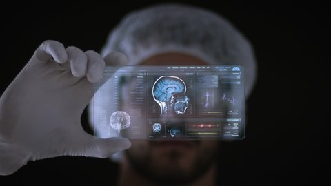 Male Scientist looking at a holographic technological interface analyzing human brain anatomy and morphology. Brain lobes, head MRI scan, neuron cell animation and vital signs. Healthcare information